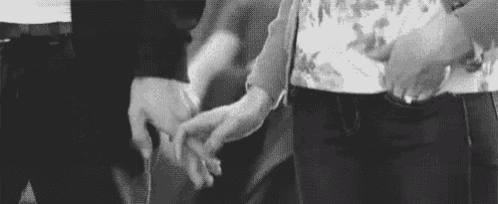 a black and white photo of a couple holding hands .