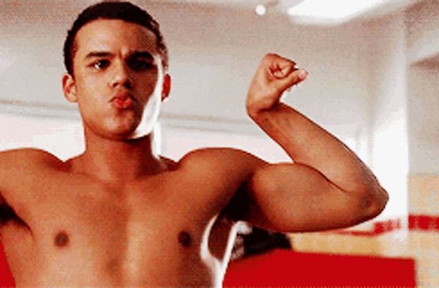 a shirtless young man is flexing his muscles