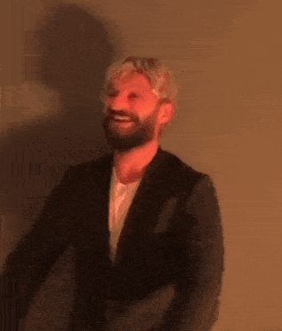 a man with a beard is holding a box in his hands and smiling .