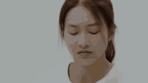 a close up of a woman 's face with her eyes closed and a ponytail .