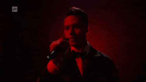 a man in a tuxedo singing into a microphone with yle on the bottom