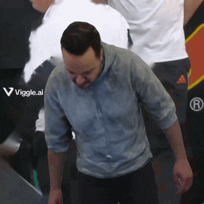 a man in a gray shirt is standing in front of a sign that says viggle.ai