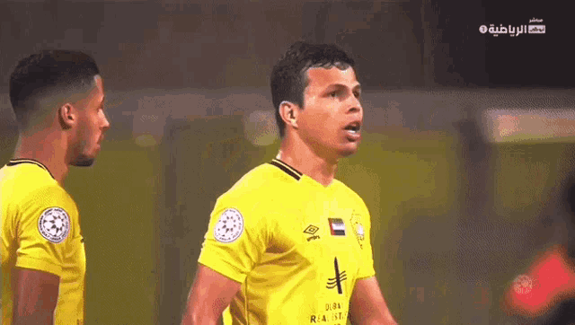 a soccer player wearing a yellow shirt with a cross on it