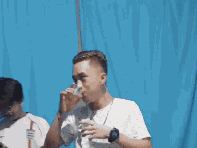 a man wearing a watch is drinking from a bottle