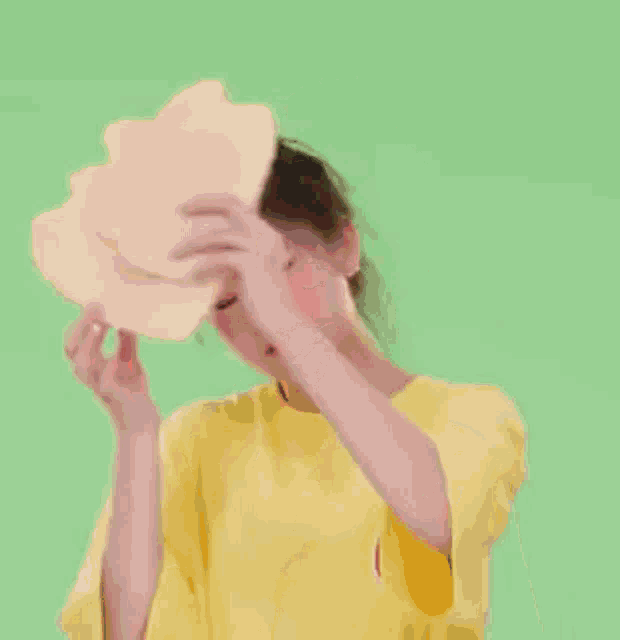 a girl in a yellow shirt is holding a slice of watermelon in her hand .