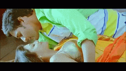 a man in a green shirt is kissing a woman in a yellow dress .