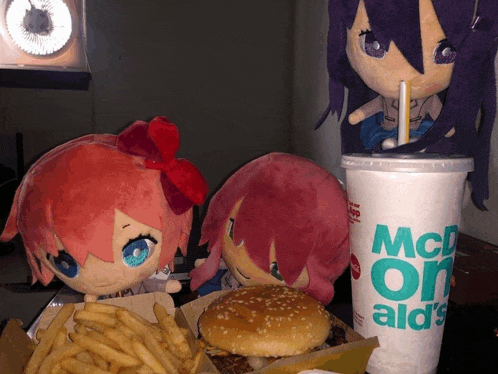 three stuffed dolls are eating a hamburger and french fries next to a mcdonalds cup