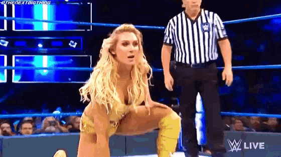 a female wrestler is kneeling down in a wrestling ring while a referee looks on .