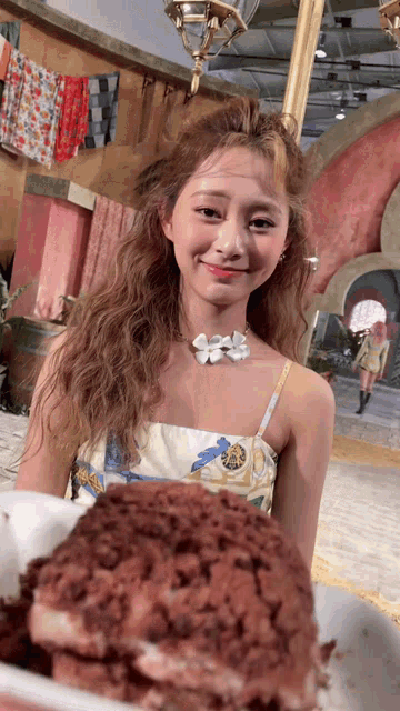 a woman in a dress is standing next to a plate of food and smiling at the camera .