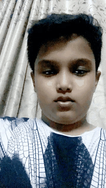 a young boy is taking a selfie with a curtain in the background