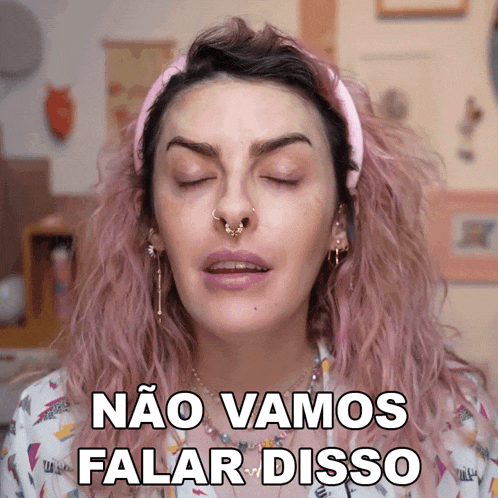 a woman with pink hair has her eyes closed and the words nao vamos falar disso above her