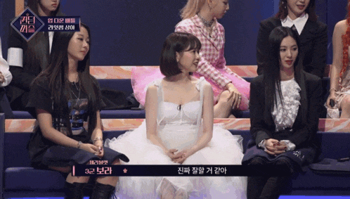 a woman in a white dress sits in a row of women