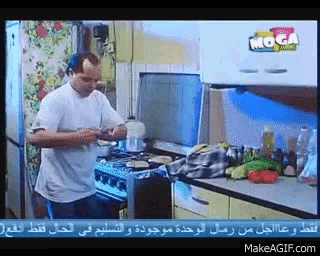a man cooking in a kitchen with a moga logo on the wall