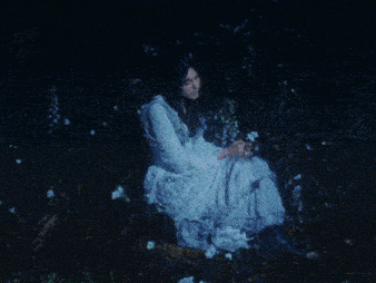 a woman in a white dress is laying on the ground with white flowers