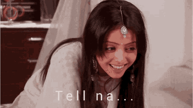 a woman in a white dress is smiling with the words tell na written below her