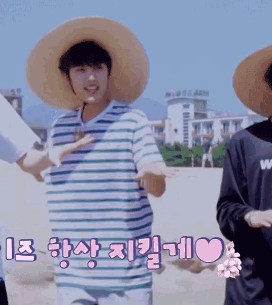 a man wearing a hat and a striped shirt stands on a beach