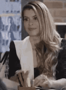 a woman is sitting at a desk in an office holding a piece of paper .