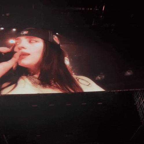 a woman singing into a microphone while wearing a hat that says mlb