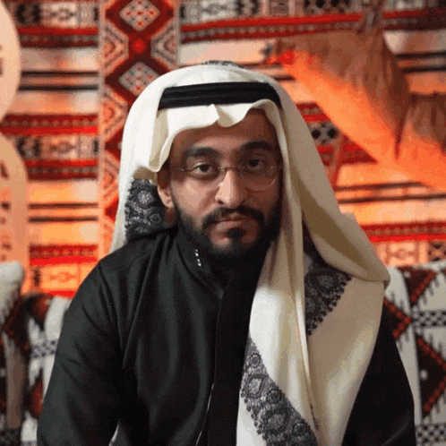 a man with a beard wearing glasses and a white scarf