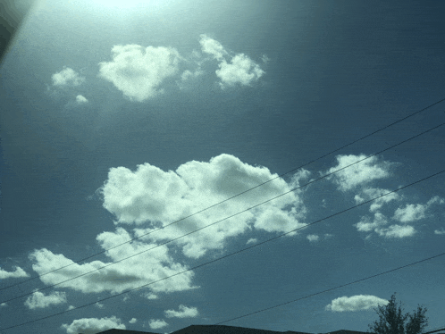 a blue sky with a few clouds and power lines in the foreground