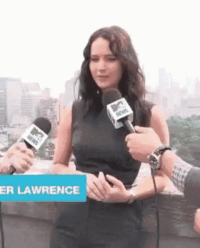a woman is talking into a mtv news microphone while standing next to a sign that says lawrence