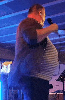 a man is singing into a microphone with a very large belly