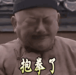 a man wearing a hat is making a funny face with his eyes closed and chinese writing on his chest .