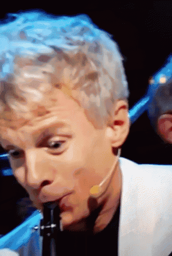 a man playing a clarinet with a microphone around his neck