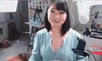 a woman in a blue shirt is sitting in a room with a microphone .
