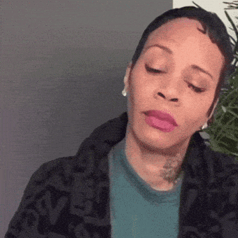 a woman with short hair and pink lipstick is wearing a black jacket and a green shirt