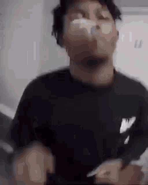 a man in a black shirt is smoking a cigarette and making a face .