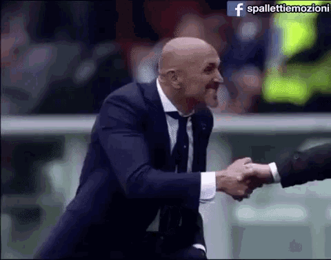 a man in a suit and tie shakes another man 's hand