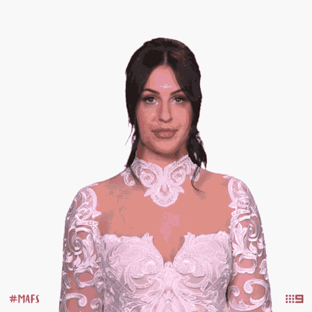 a woman in a white lace dress winks and holds up her hand