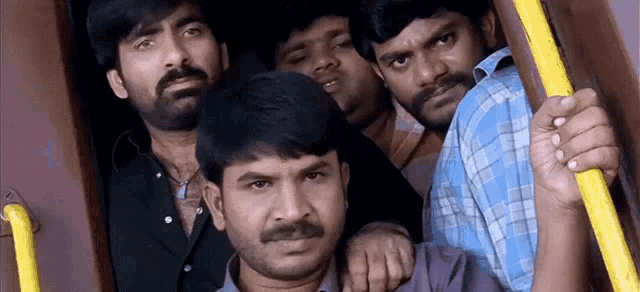 a group of men are standing next to each other on a bus and looking at the camera .