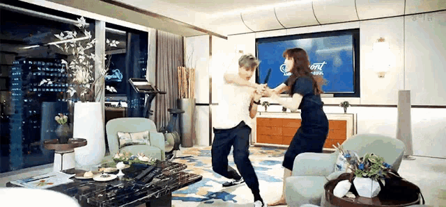 a man and a woman are dancing in a living room in front of a large flat screen tv .
