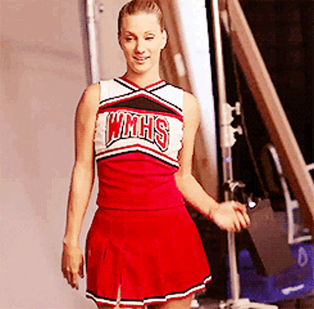 a cheerleader wearing a wmhs uniform stands in front of a staircase