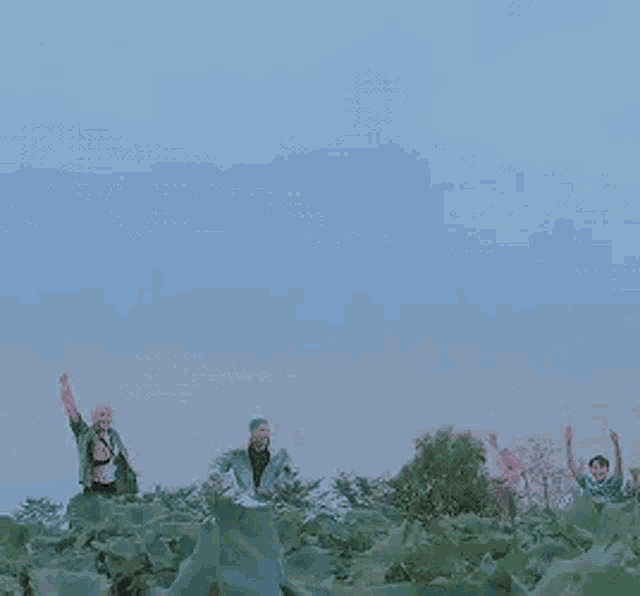 a group of people are jumping in the air in a field with their arms in the air .