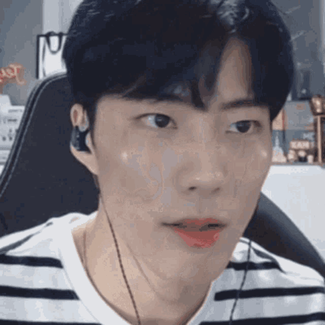 a man wearing headphones and a striped shirt looks at the camera .
