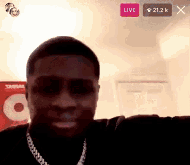 a man wearing sunglasses and a chain is sitting on a couch in a living room .