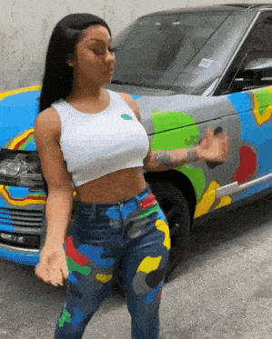 a woman is standing in front of a colorful range rover .