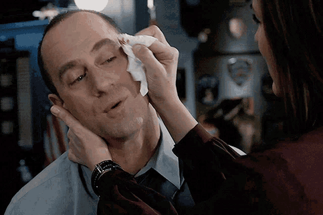 a woman wipes a man 's forehead with a napkin