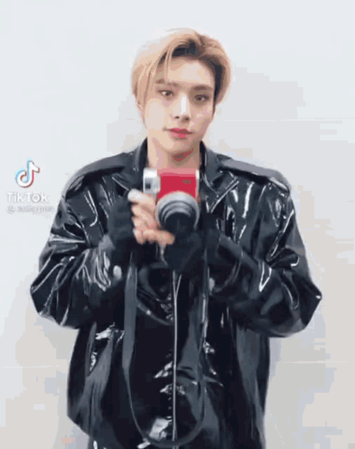 a man in a black leather jacket is holding a camera .