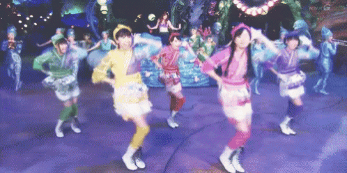 a group of girls are dancing on a stage with purple background