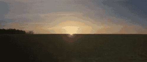 the sun is setting in the distance over a field