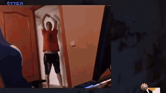 a man in a red shirt is standing in a doorway with his arms outstretched .