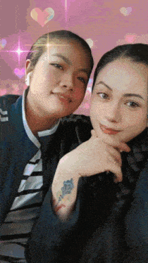 two women are posing for a picture and one has a tattoo on her arm