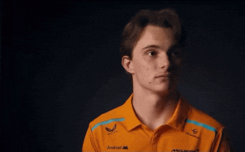 a young man wearing a mclaren shirt looks at the camera