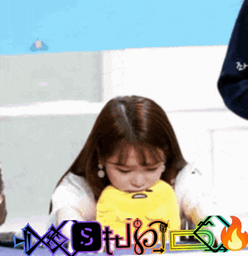 a woman sitting at a table with a yellow stuffed animal in front of a sign that says ' studio '