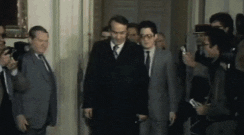 a group of men in suits and ties are walking through a doorway