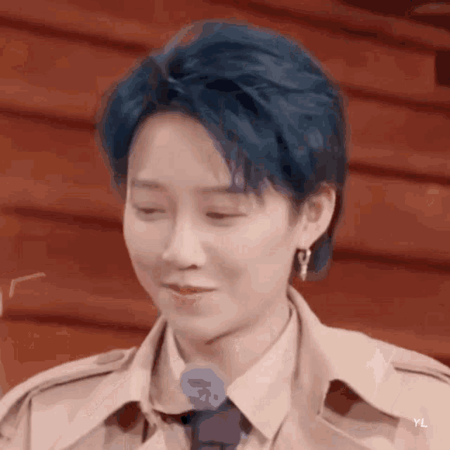 a close up of a person 's face with blue hair and earrings .